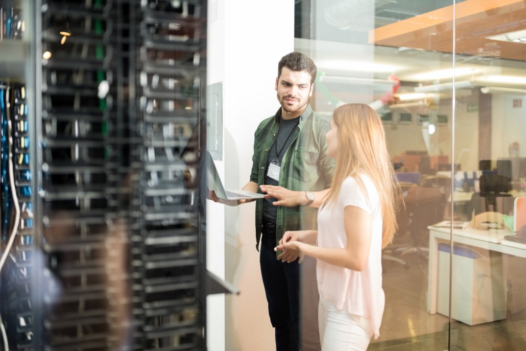 two business people standing server room with laptop discussing 1